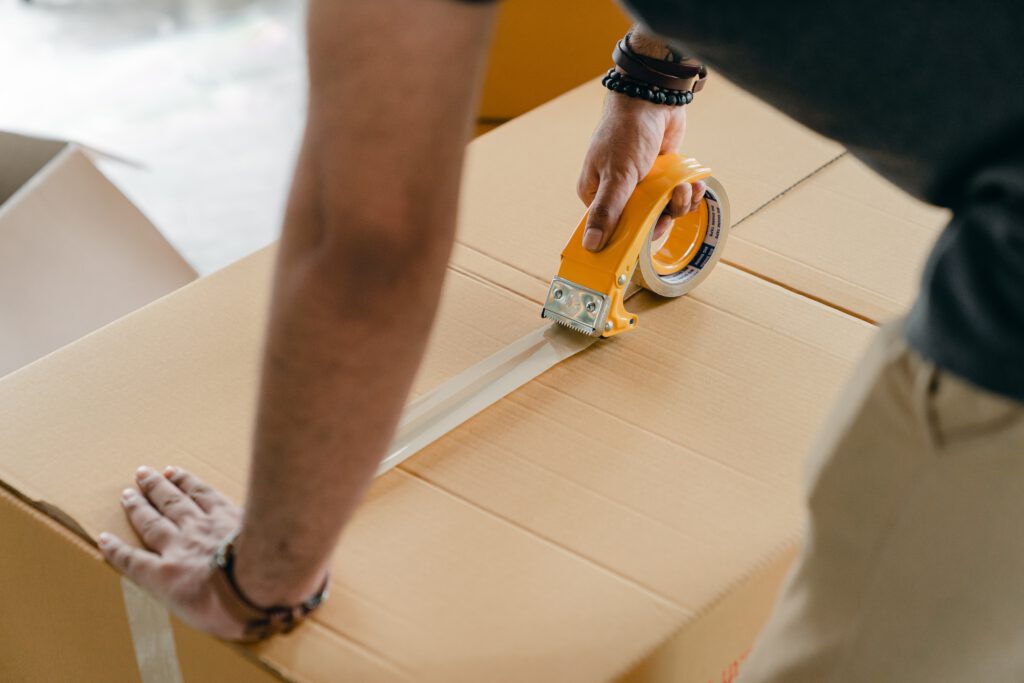 Ein Mann, der ein Paket mit Klebeband zuklebt.